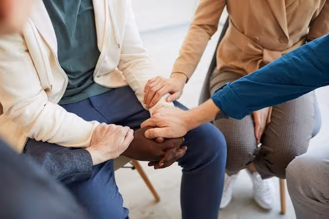 People holding hands in a supportive grief counseling group